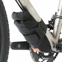 A black Restrap downtube bag attached to a bicycle frame beneath the downtube, featuring a roll-top closure and velcro strap.