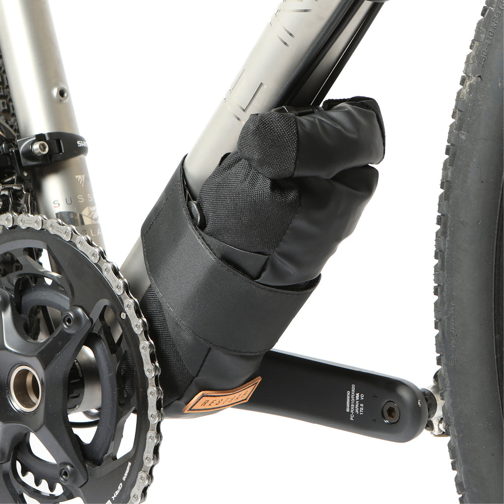 A black Restrap downtube bag attached to a bicycle frame beneath the downtube, featuring a roll-top closure and velcro strap.