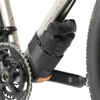A black Restrap downtube bag attached to a bicycle frame beneath the downtube, featuring a roll-top closure and velcro strap.