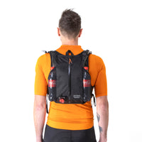 Rear of the Restrap race hydration vest on a man, showing the reflective label and zip compartment and side pockets