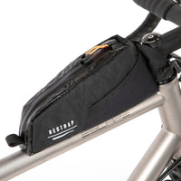 A black Race Top Tube Bag attached to the top tube of a bicycle, featuring a YKK aquaguard zip and reflective detailing.