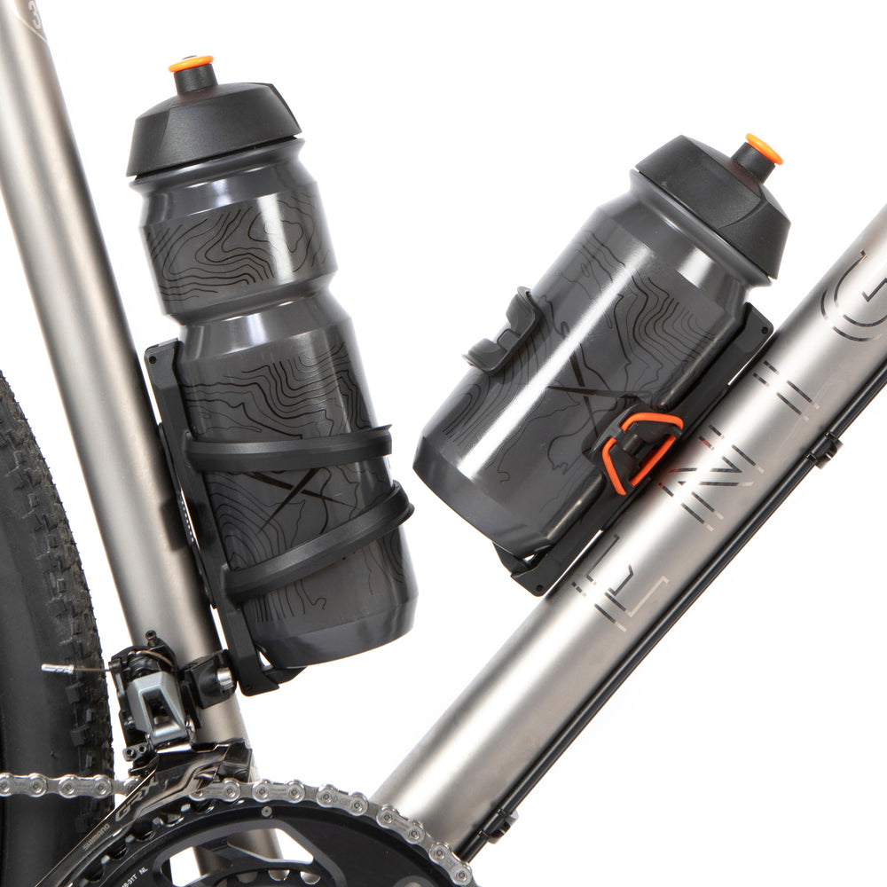 A black side release bottle cage mounted on a bicycle frame, with a side entry opening.