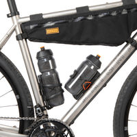 A black side release bottle cage mounted on a bicycle frame, with a side entry opening.