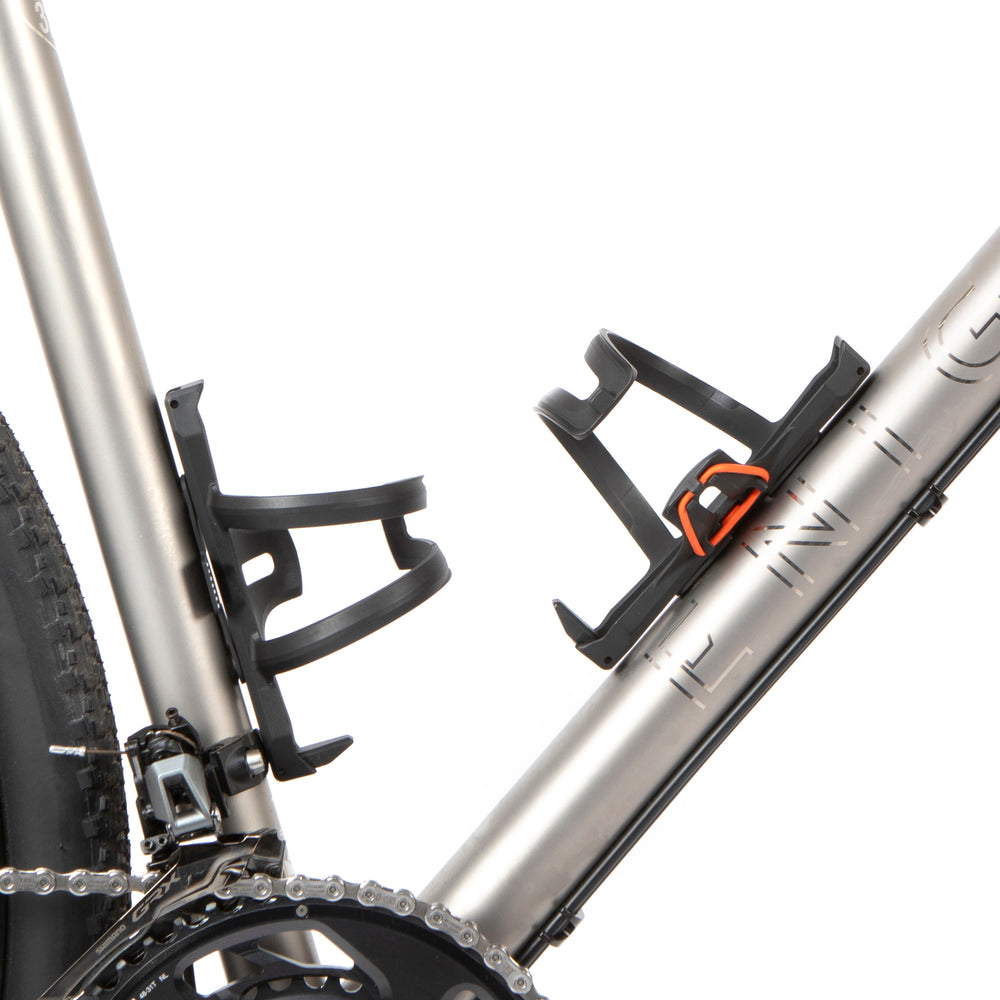 A black side release bottle cage mounted on a bicycle frame, with a side entry opening.