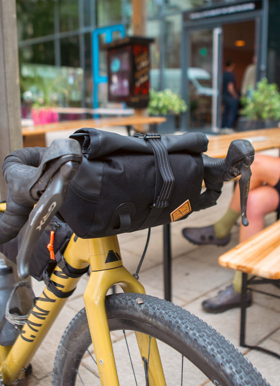 restrap rolltop canister bag leant up against a table in an urban setting