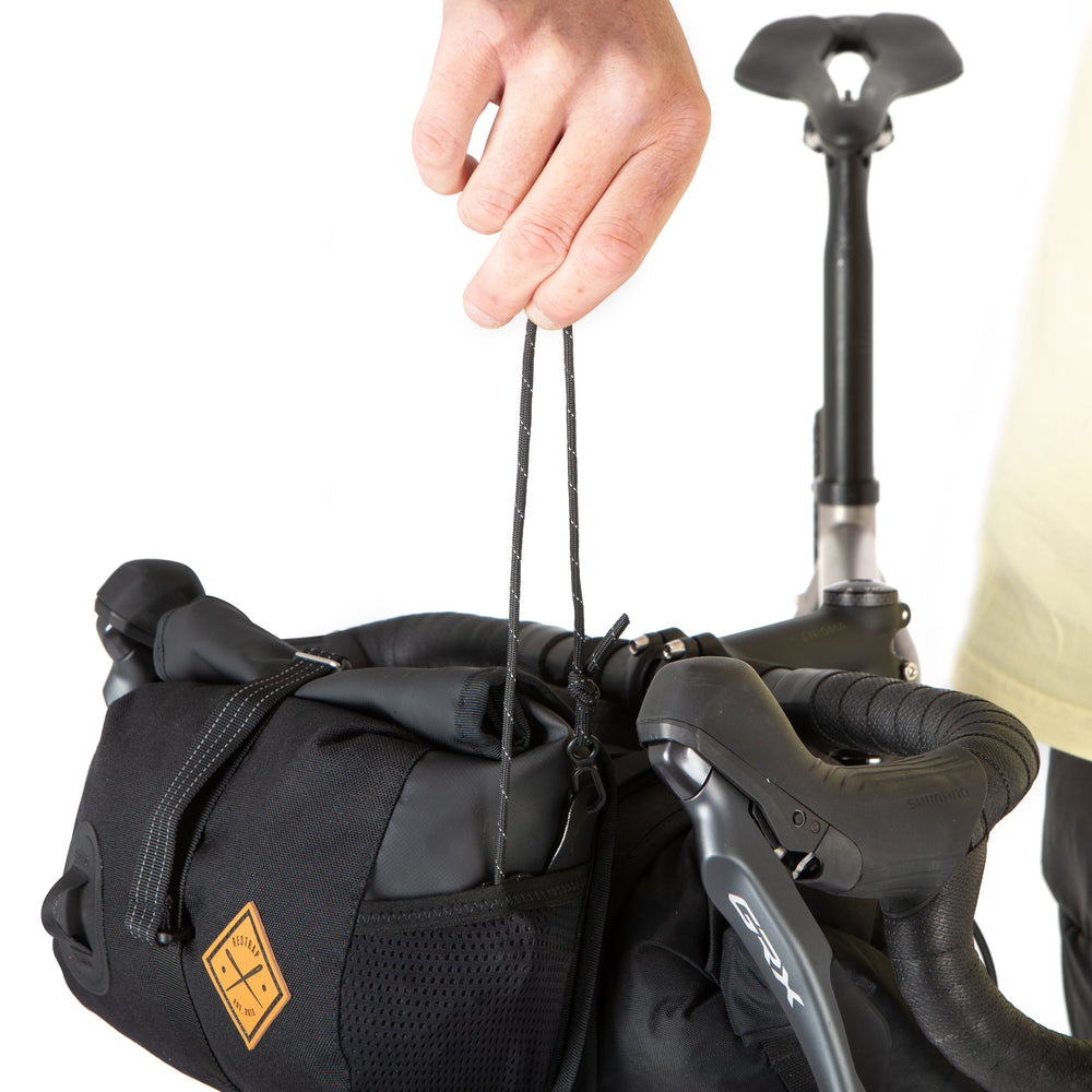 A black Restrap Holster Bar Bag Plus showing shoulder strap being removed