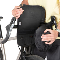 A black Restrap Holster Bar Bag Plus mounted on a bicycle handlebar with the dry bag being removed from the holster