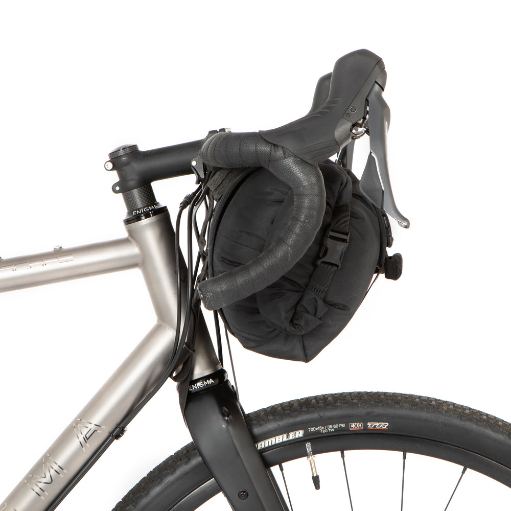 A side on image of a restrap holster bar bag attached to the handlebars of a bicycle, designed for bikepacking.