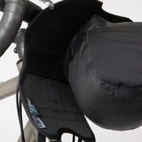 A black Race Bar Bag attached to the handlebars of a bicycle, featuring a holster system and a roll-top dry bag - this is attached to drop handlebars. The dry bag is being removed from the holster