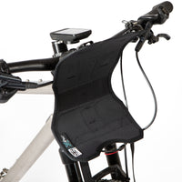 A black Race Bar Bag holster attached to the handlebars of a bicycle, featuring a holster system and a roll-top dry bag - this is attached to flat handlebars on a mountain bike