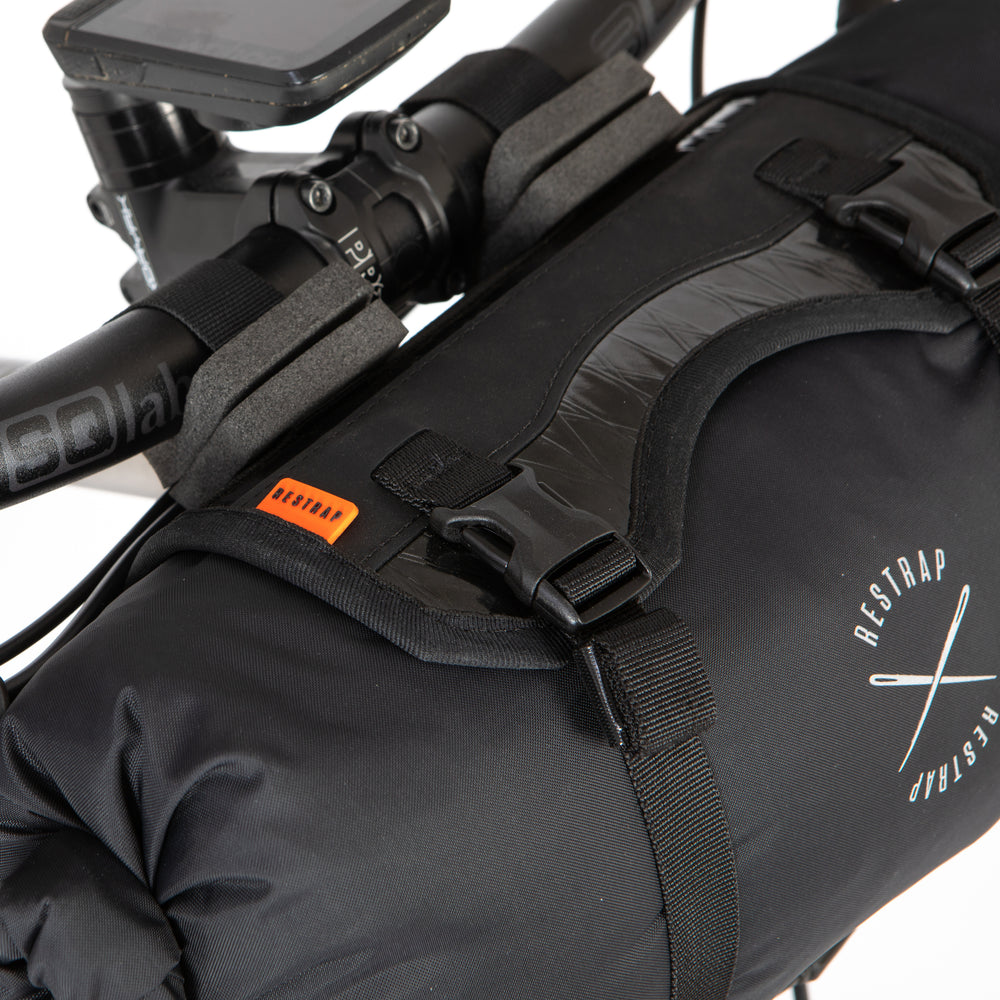 Black bikepacking bag with straps attached to a bicycle handlebar, featuring the Restrap logo.