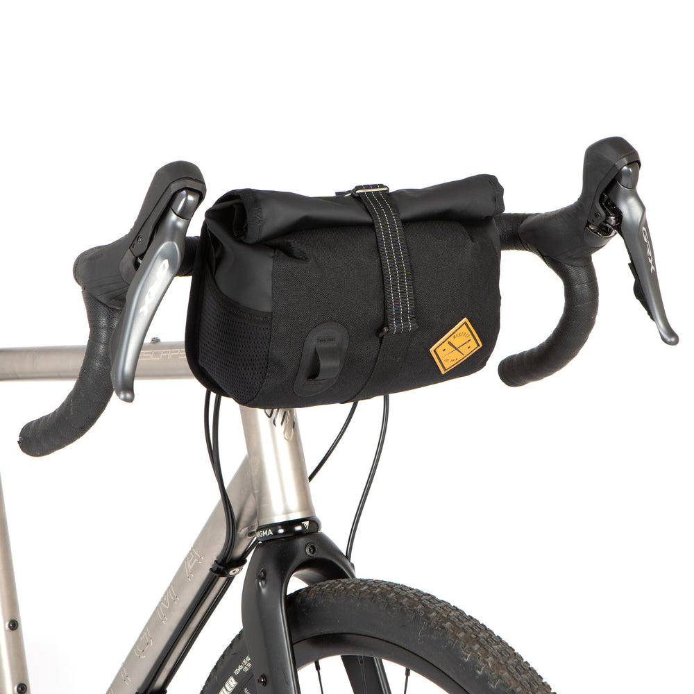 A black Rolltop Canister Bag attached to the handlebars of a bicycle, featuring a waterproof design with a capacity of 4L and a Fidlock buckle.