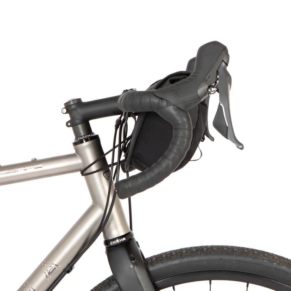 A black Rolltop Canister Bag attached to the handlebars of a bicycle, featuring a waterproof design with a capacity of 4L and a Fidlock buckle.