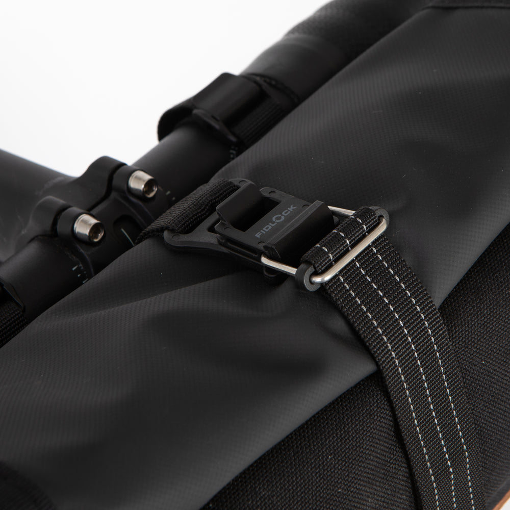 Close-up of a Rolltop Canister bag with a strap and buckle on a white background