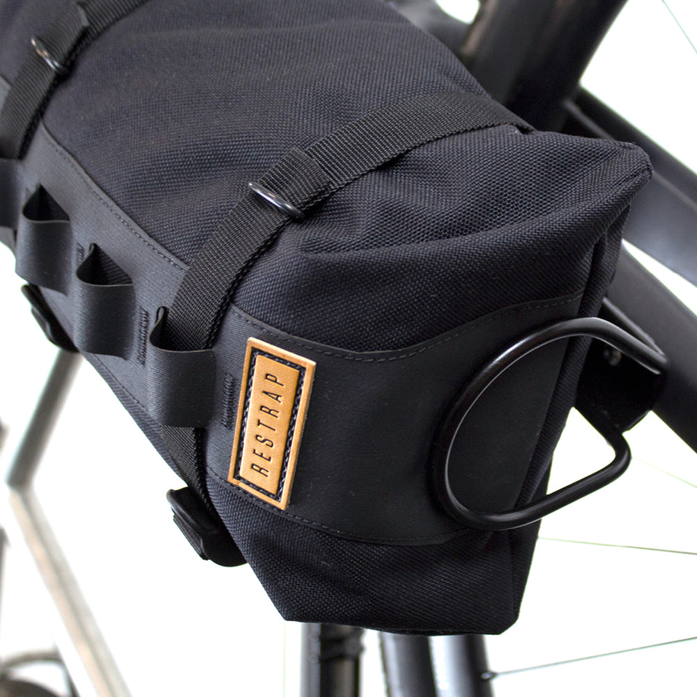 The underneath of a black Restrap Fork Bag attached to a bicycle fork cage, designed to be waterproof and carry 5 liters.