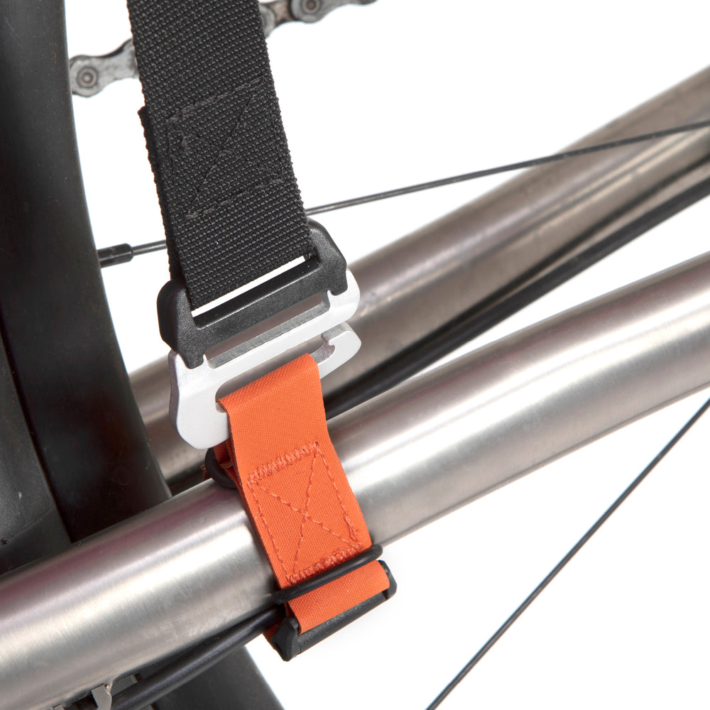 A black hike a bike harness attached to the frame of a bicycle, designed for carrying the bike on one's back.