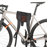 A black hike a bike harness attached to the frame of a bicycle, designed for carrying the bike on one's back.