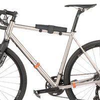 A black hike a bike harness attached to the frame of a bicycle, designed for carrying the bike on one's back.