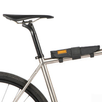 A black hike a bike harness attached to the frame of a bicycle, designed for carrying the bike on one's back.