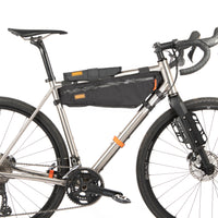 A black hike a bike harness attached to the frame of a bicycle, designed for carrying the bike on one's back.