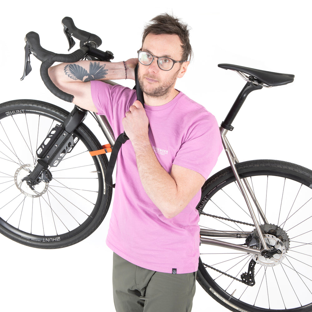 A black hike a bike harness attached to the frame of a bicycle, designed for carrying the bike on one's back.