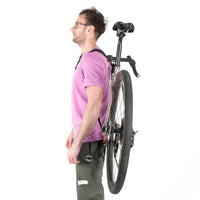 A black hike a bike harness attached to the frame of a bicycle, designed for carrying the bike on one's back.