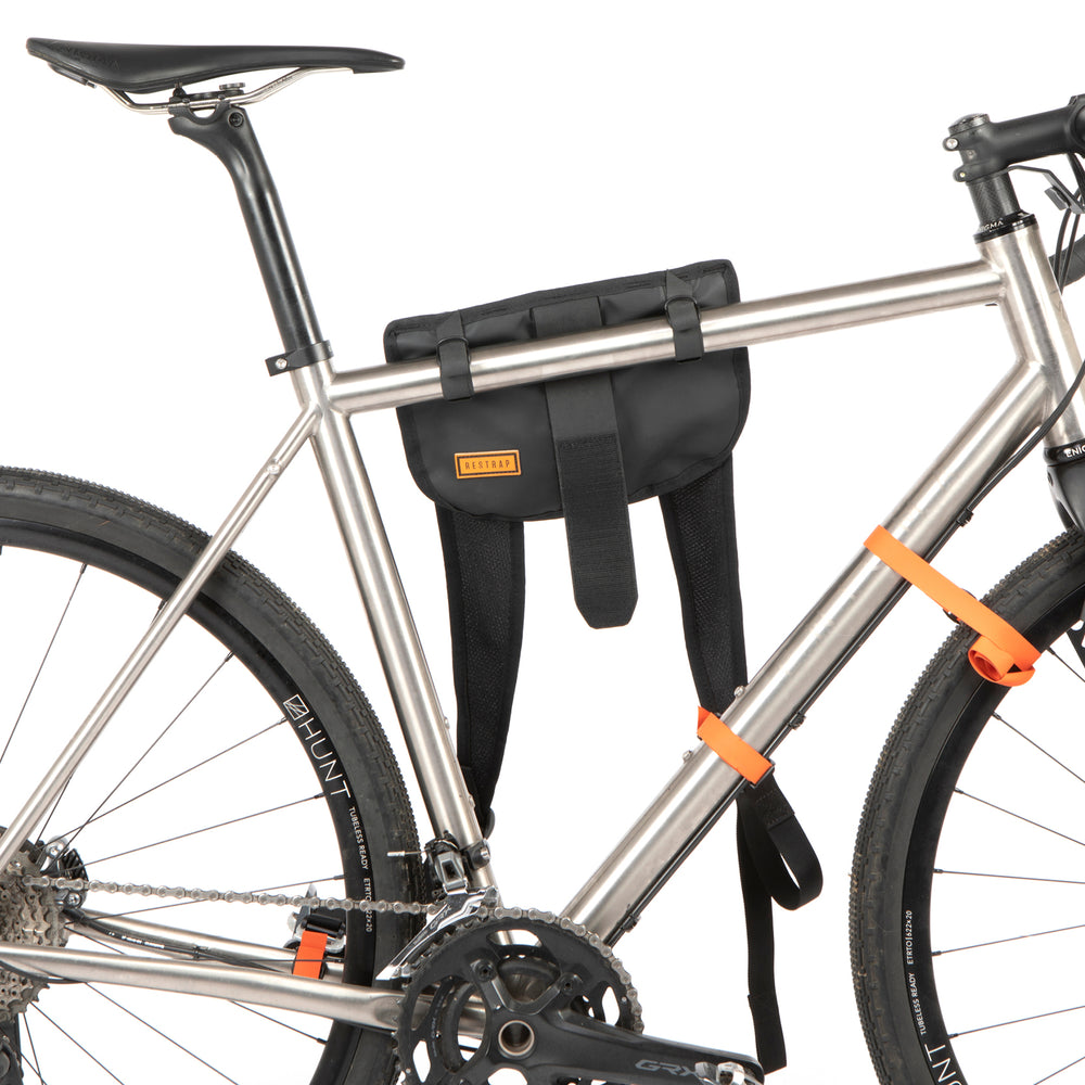 A black hike a bike harness attached to the frame of a bicycle, designed for carrying the bike on one's back.