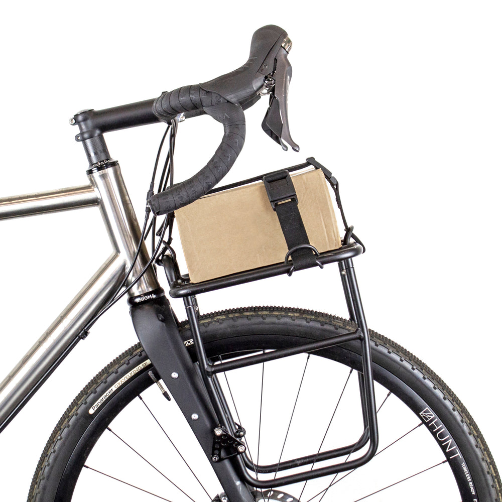 Restrap luggage straps with rubber o-rings and magnetic buckles on a white background holding a box onto a front rack on a bicycle