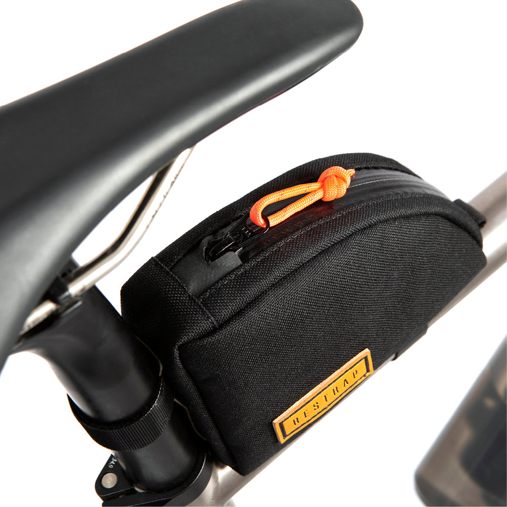 A black Rear Top Tube Bag attached to the top tube of a bicycle just below the seat, featuring a simple zip closure and a small label with the brand name.