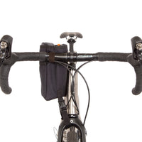 A black Restrap stem bag mounted on the handlebar of a bicycle, shown from the front