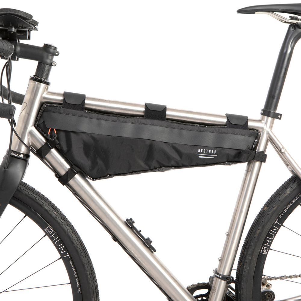 A black Restrap Race Frame Bag large attached to the frame of a bicycle, designed to hold essentials while riding.