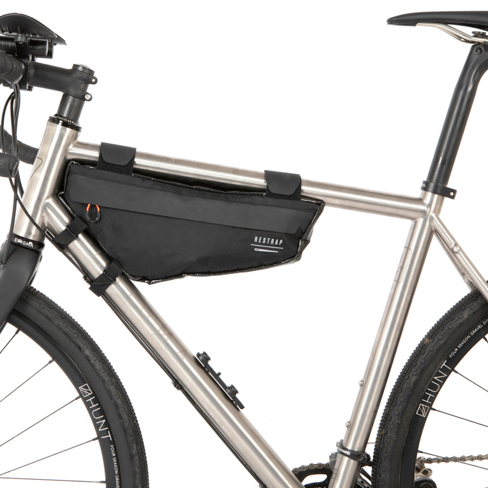 A small black race frame bag attached to the frame of a bicycle, designed for bikepacking.