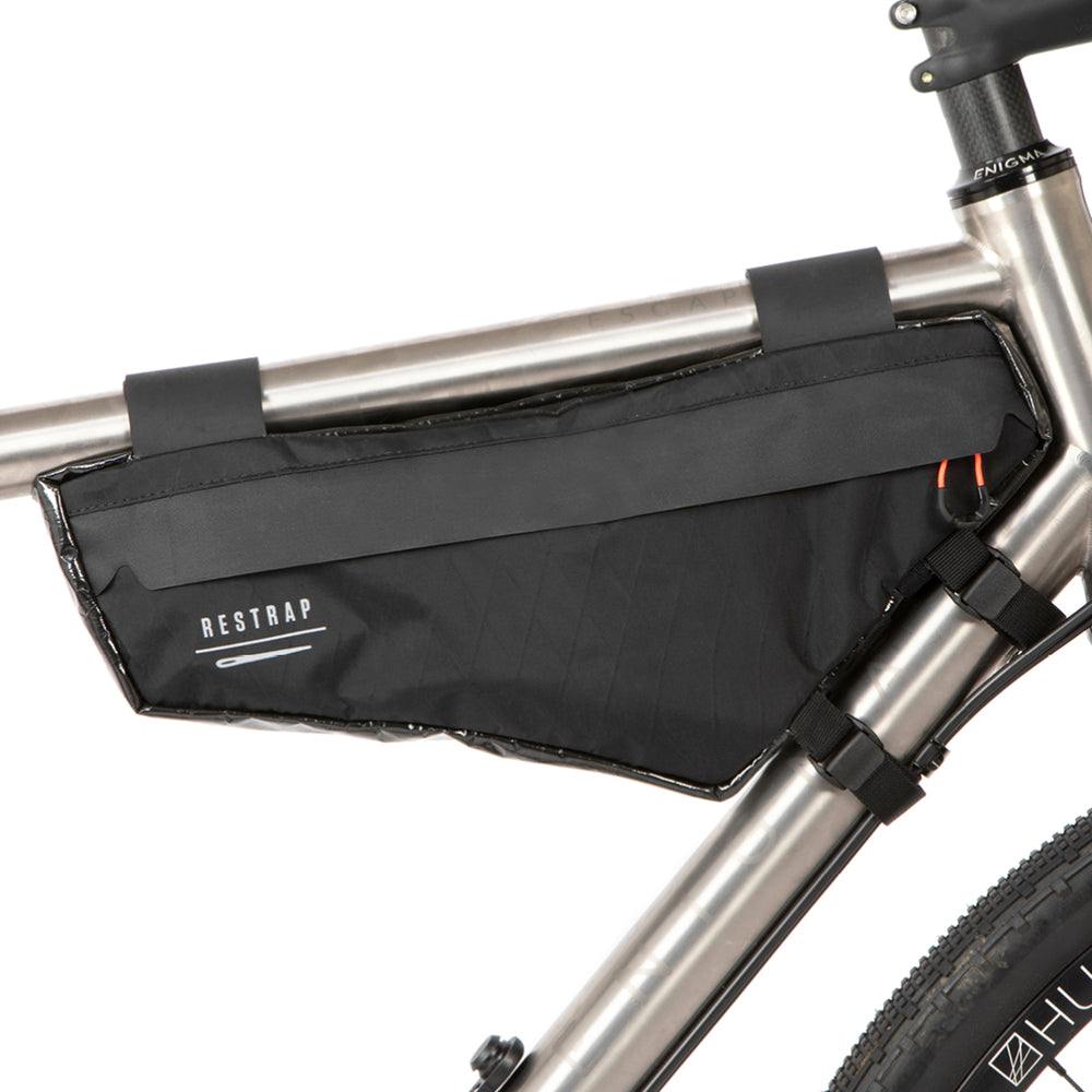 A small black race frame bag attached to the frame of a bicycle, designed for bikepacking.