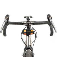 A black metal bumper bar mounted on a bicycle handlebar with a small wrap attached