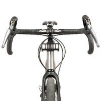 A black metal bumper bar mounted on a bicycle handlebar designed for spacing a handlebar bag further outwards and upwards