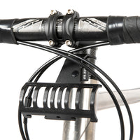 A black metal bumper bar mounted on a bicycle handlebar designed for spacing a handlebar bag further outwards and upwards