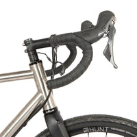 A black metal bumper bar mounted on a bicycle handlebar designed for spacing a handlebar bag further outwards and upwards