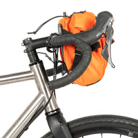 A black metal bumper bar mounted on a bicycle handlebar designed for spacing a handlebar bag further outwards and upwards