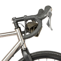 A black metal bumper bar mounted on a bicycle handlebarwith a jacket attached for storage
