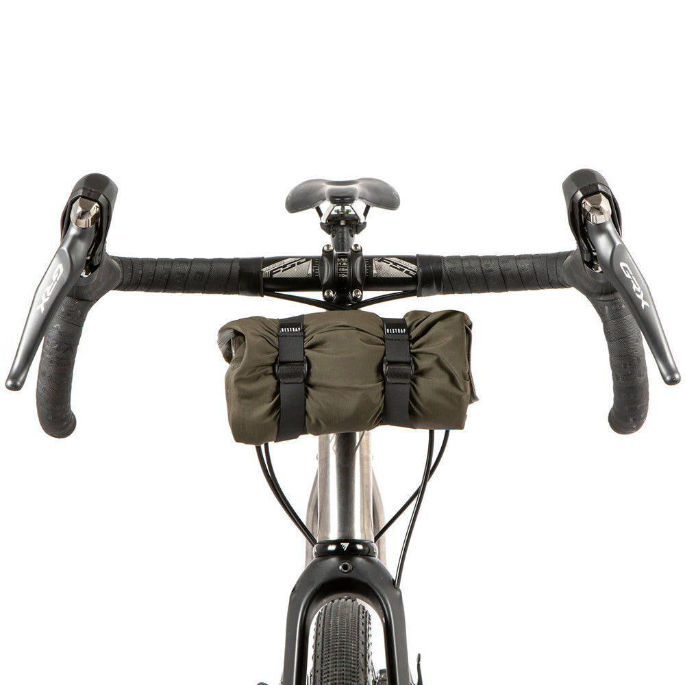 A black metal bumper bar mounted on a bicycle handlebarwith a jacket attached for storage