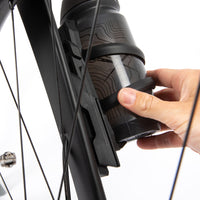 Person installing a black bicycle water bottle holder on a bike frame with switch multi mount