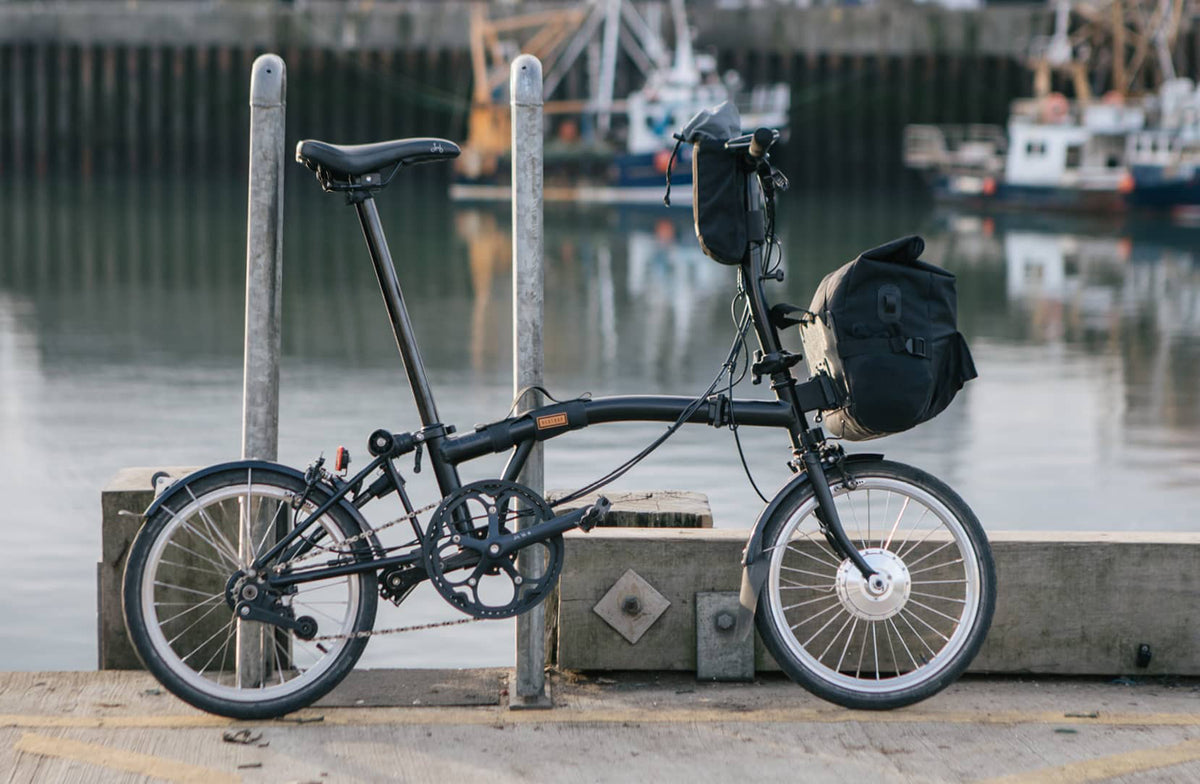 brompton bike with restrap folding bike bags attached in front of a dock