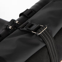 Close-up of a Rolltop Canister bag with a strap and buckle on a white background